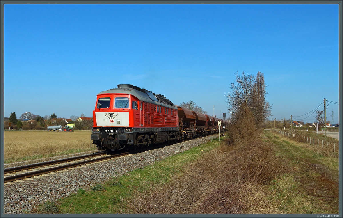 Während der Bauer sein Feld düngt, verlässt 232 909-2 der DB Cargo mit dem Schotterzug 60408 Dönstedt - Magdeburg-Rothensee den Bahnhof Groß Ammensleben. Die Ludmilla ist eine der zeitweise in den Niederlanden eingesetzten Maschinen und trägt daher eine größere Kontrastfläche ( Hollandlatz ). (30.03.2021)