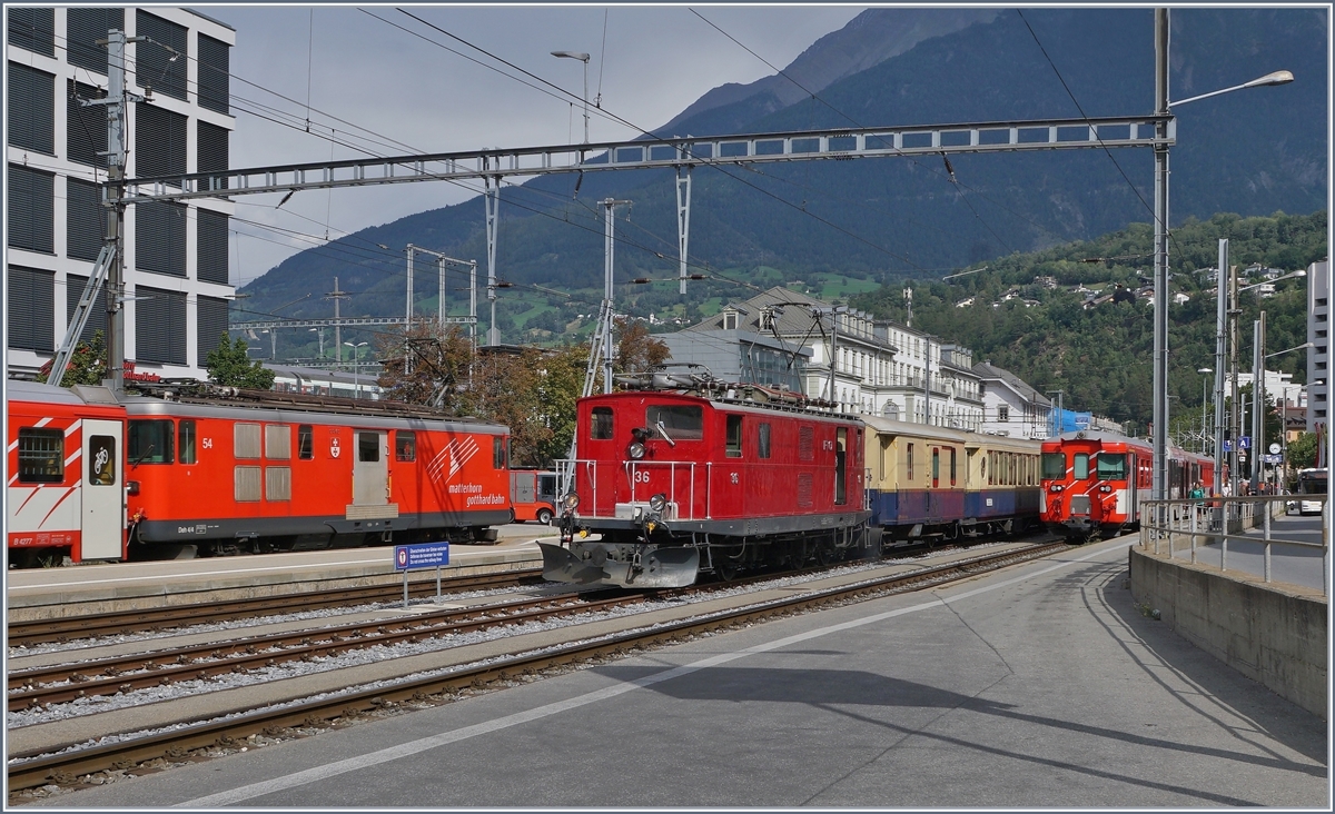 Während der Deh 4/4 54 mit seinem Regionalzug 549 von Andermatt nach Visp Brig verlässt und der Gegenzug nach Fiesch auf die Abfahrt wartet, bildet die historische HGe 4/4 36 mit ihrem Glacier Pullman Express von St. Moritz nach Zermatt einen herrlichen Kontrast.

31. August 2019
