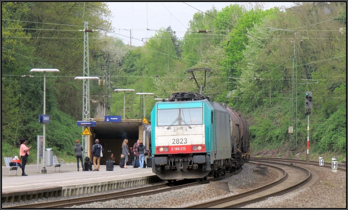 Während die Fahrgäste auf ihren Zug warten,kommt die Cobra 2823 mit einen langen Kesselwagenzug durch den Bahnhof Eschweiler (Rhl) gefahren. Szenario vom Bahnsteig aus am 01.Mai.2015.