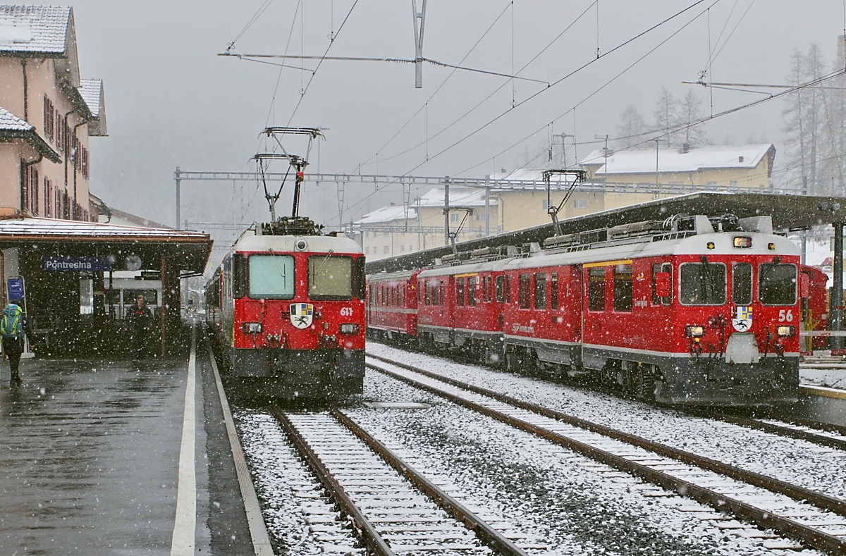 Während die Ge 4/4 II 611 noch auf die Abfahrt warten muss, verlassen die ABe 4/4 56 und 54 mit einem Zug von Tirano nach St. Moritz während eines heftigen Schneeschauers am 30.03.2022 den Bahnhof Pontresina