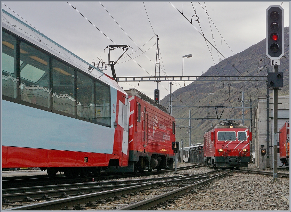 Während die MGB HGe 4/4 II 105 mit ihrem Regionalzug nach Visp in Andermatt auf die Abfahrt wartet, rangiert eine weitere MGB HGe 4/4 II, um ihren Zug nach Disentis zu umfahren.
Das Bild entstand am westlichen Ende des Bahnsteiges Gleis 2/3.   
21. Okt. 2017

