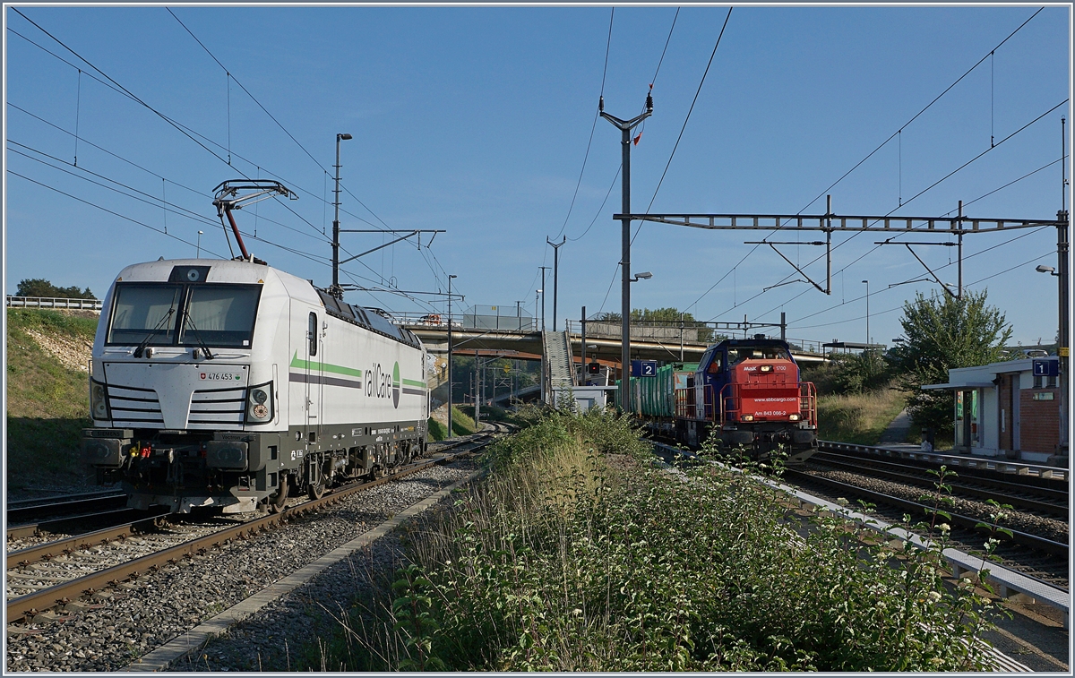 Während die Rail Care Rem 476 453 in Vufflens la Ville rangiert, fährt die SBB Cargo Am 843 066-2 mit einem  Tridel -Güterzug durch.
29. August 2018