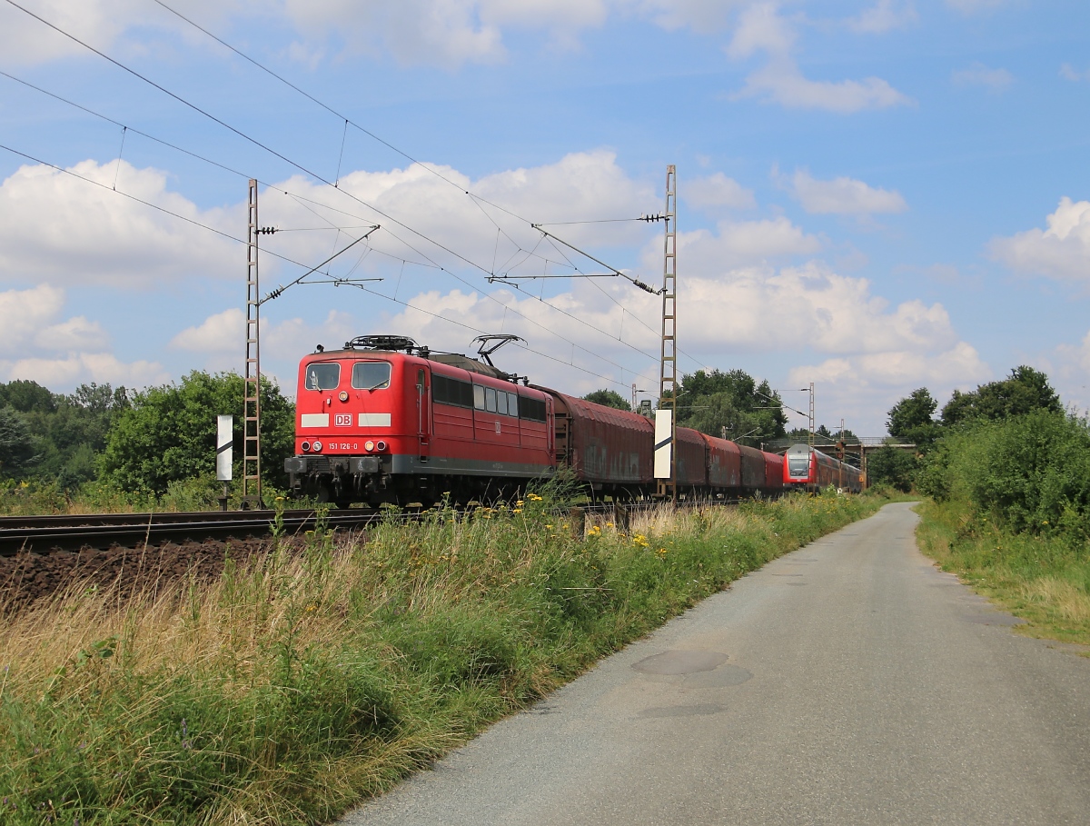 Während der RE gerade im Zulauf auf Eystrup aus dem Bild verchwindet, kommt aus Richtung Norden die 151 126-0 mit einem Ganzzug aus Schiebeplanwagen. Aufgenommen am 22.07.2014.