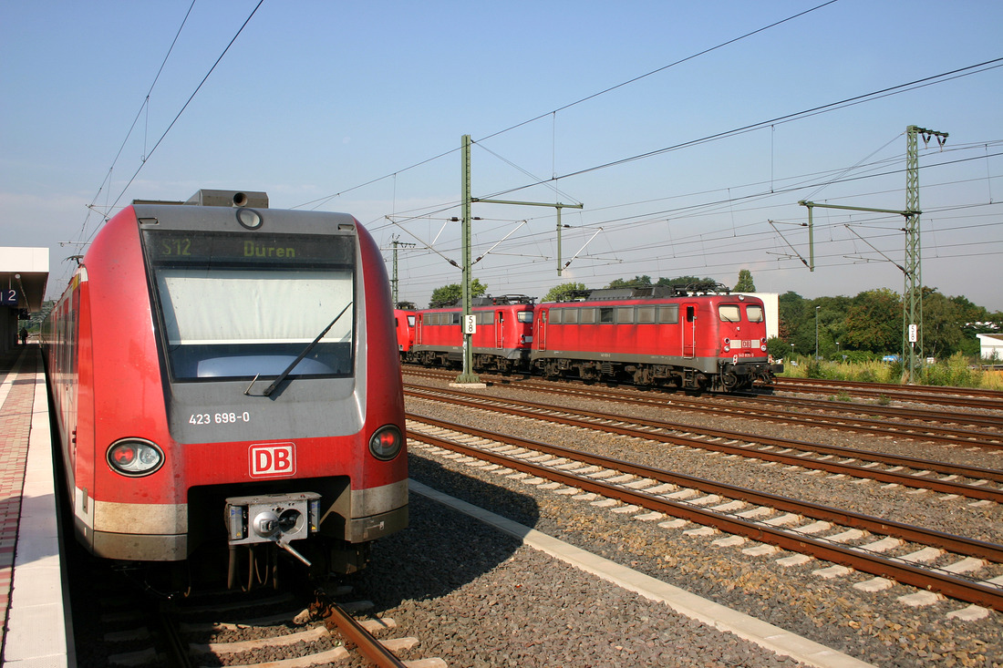 Während seiner Haltezeit in der Station  Köln-Müngersdorf Technologiepark  begegnet 423 198 einem Lokzug
an dessen Ende die verkehrsrote 140 835 hängt. Aufnahmedatum: 3. September 2004