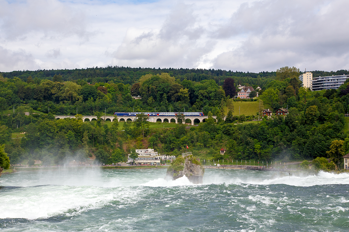 
Während tobend die Wassermassen den Rheinfall bei Schaffhausen herab stürzen, fährt eine SBB Re 450 mit Doppelstock-Pendelzügen am 18.06.2016, als S 9 (Uster – Zürich HB – Schaffhausen) der S-Bahn Zürich, über den Hangviadukt in Neuhausen am Rheinfall und erreicht bald die gleichnamentliche Station.