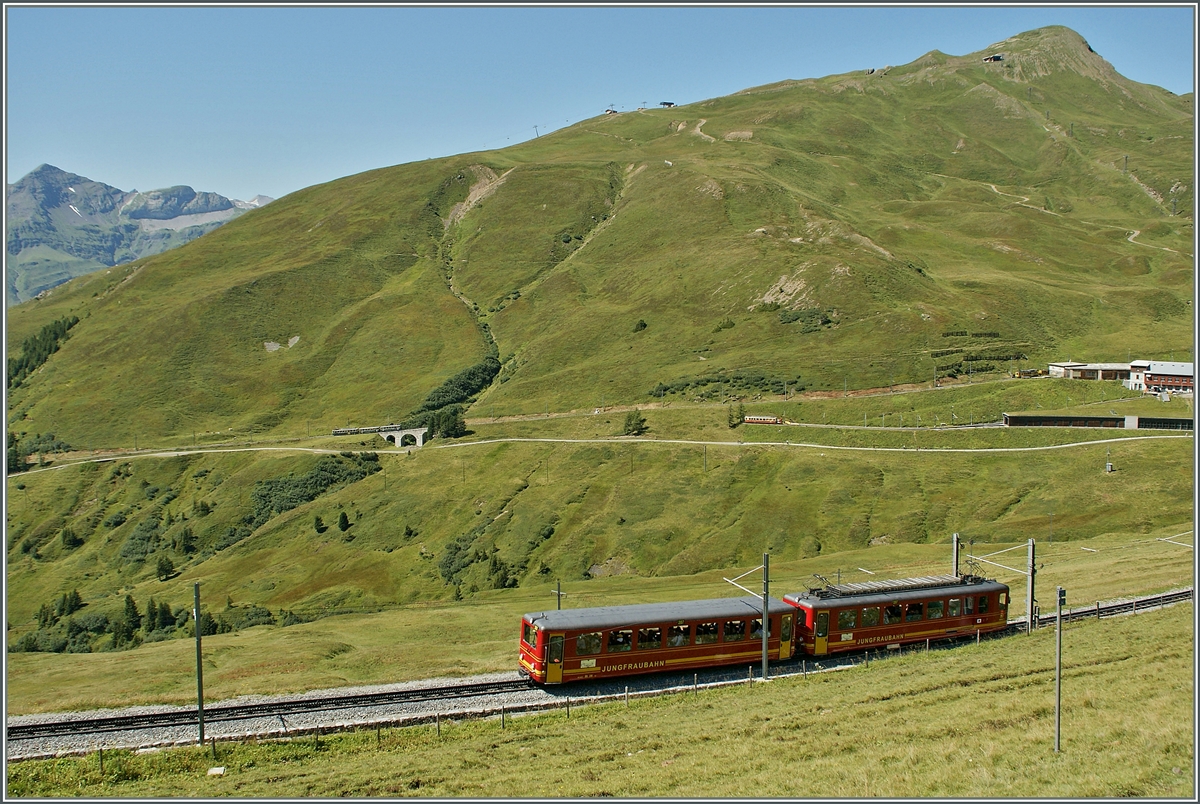 Während im Vordergrung ein älterer Jungfraubahn-Triebzug dem Jungfraujoch zu strebt, ist im Hintergrund ein talwärtsfahrender WAB Zug zu erkennen.
Ganz rechts im Bild, und nur angedeutet, die Station  Kleine Schiedegg .
21. Aug. 2013