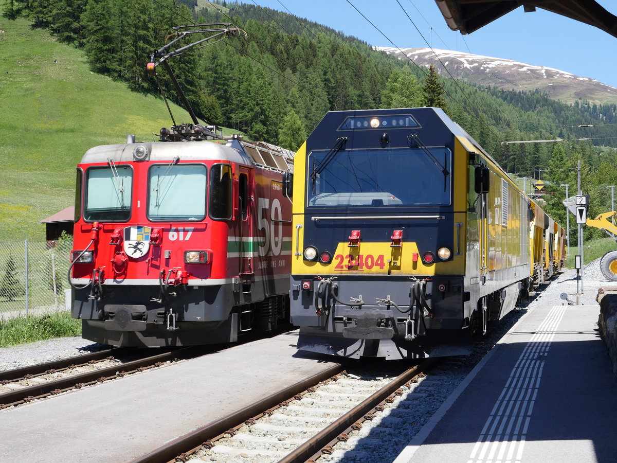 Während die Waggons an der Diesellok Gmf 4/4 D4 23404 mit Schotter beladen werden schiebt Ge 4/4 II 617  ILANZ  mit Werbung  50 Jahre LGB  den R 1828 von Filisur nach Davos Platz; Davos-Glaris, 13.06.2019 
