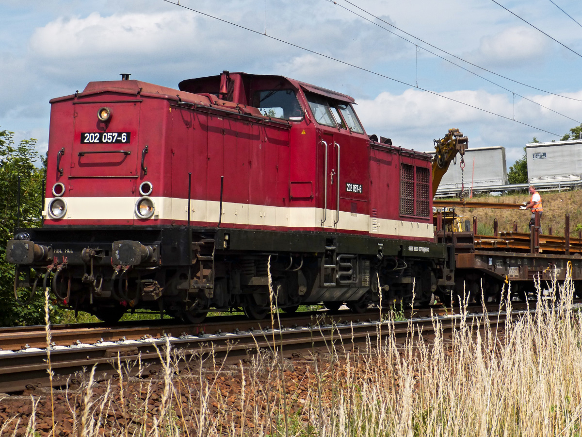 Wärhend 202 057-6 mit ihrem KVD-Motor stehend vor sich hin dieselt, werden dahinter die Gleise mittels Bagger entladen. Nordhausen, Ortsrand Richtung Westen 15.07.2015