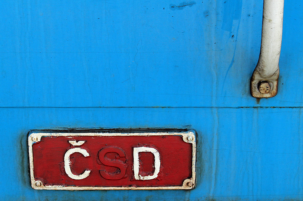 Was macht man mit fest angebrachten und massiven Schildern an Eisenbahnfahrzeugen, wenn der Inhalt nicht mehr ganz richtig ist? Das kann man ganz pragmatisch lösen, wie hier bei einem Wagen des Eilzugs Sp 1965 am 12.09.2015 im Bahnhof Železná Ruda-Alžbětín zu sehen: Die Teilung der Tschechoslowakei im Jahre 1993 brachte auch 2 eigene Bahnverwaltungen mit sich, für Tschechien wurde aus der ehemaligen ČSD die České dráhy ČD gebildet. Das Eigentumsschild stimmte nun nicht mehr, aber anstatt das schöne massive Schild zu entfernen und durch ein Neues zu ersetzen, wurde einfach das  S  rot übermalt, so wurde eben aus  ČSD  das nunmehr aktuelle  ČD . So einfach kann man das regeln....