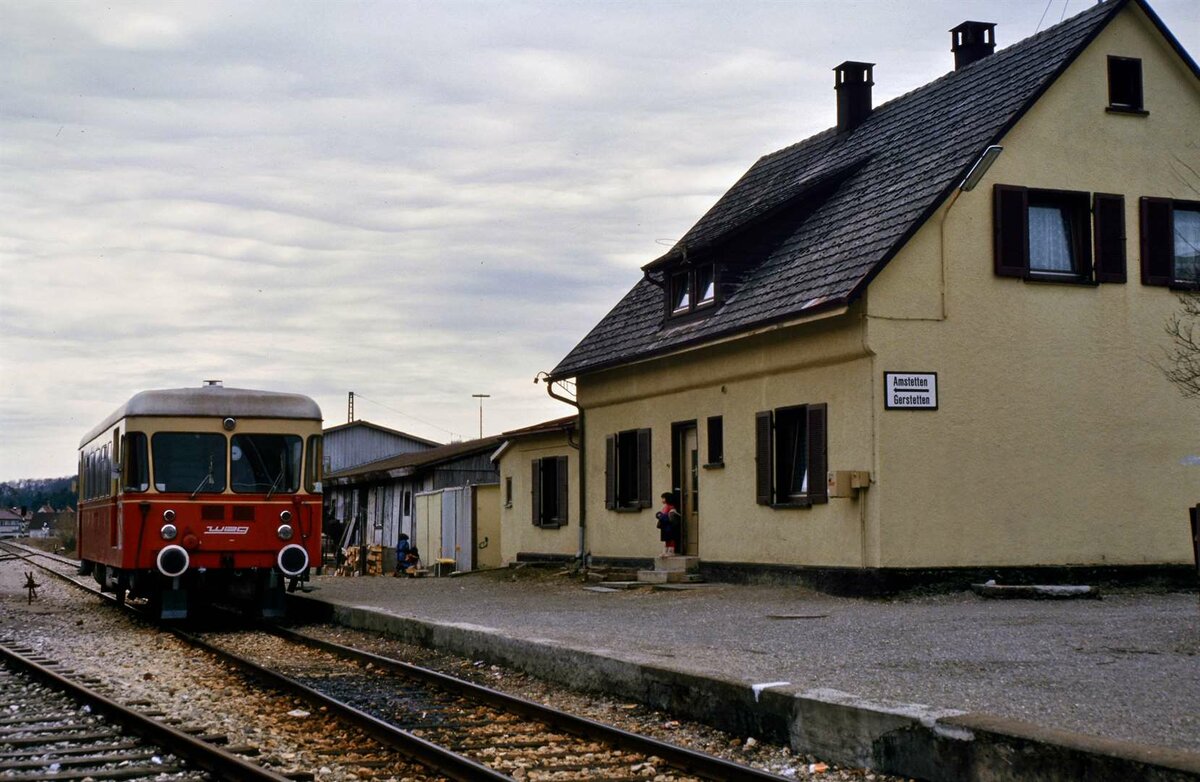 WEG-Bahnhof Amstetten Lokalbahn mit Fuchs-Triebwagen. Der WEG-Lokalbahnhof befindet sich neben den Gleisen der DB auf einem eigenen Areal mit einem eigenen Bahnhofsgeb�ude. Vor allem die Bundeswehr nutzte diese nichtbundeseigene Eisenbahn. Das Geb�ude auf dem Foto ist �brigens nicht das Bahnhofsgeb�ude, es ist nur ein Wohnhaus mit Hinweisschild auf die Lokalbahn. Mittlerweile befinden sich dort rechts vom Triebwagen eine Wiese und Parkpl�tze.
Datum: 01.04.1985