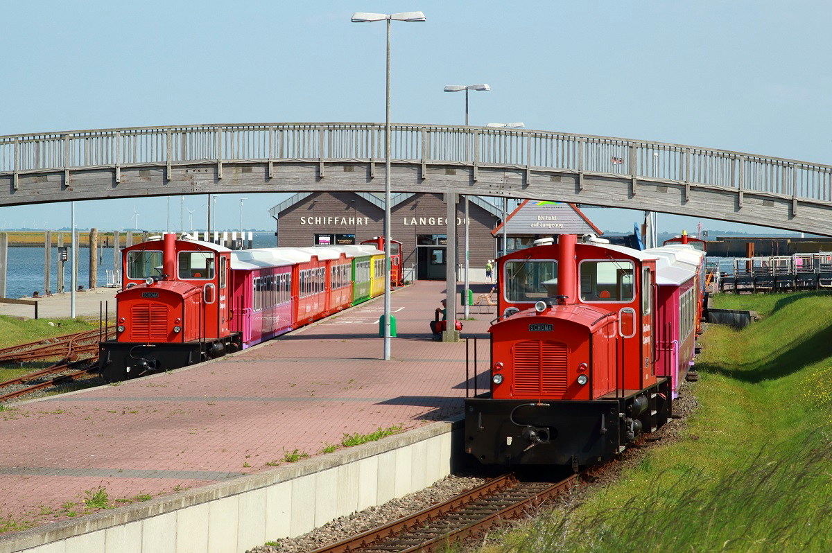 Wegen des starken Urlaubervekehrs am Pfingstwochenende setzte die Langeooger Inselbahn am 02.06.2017 beide Zuggarnituren ein, die hier am Anleger auf das Fährschiff warten. Links die Garnitur mit den Lokomotiven 4 und 2, den rechten Zug befördern die Lokomotiven 5 und 1.