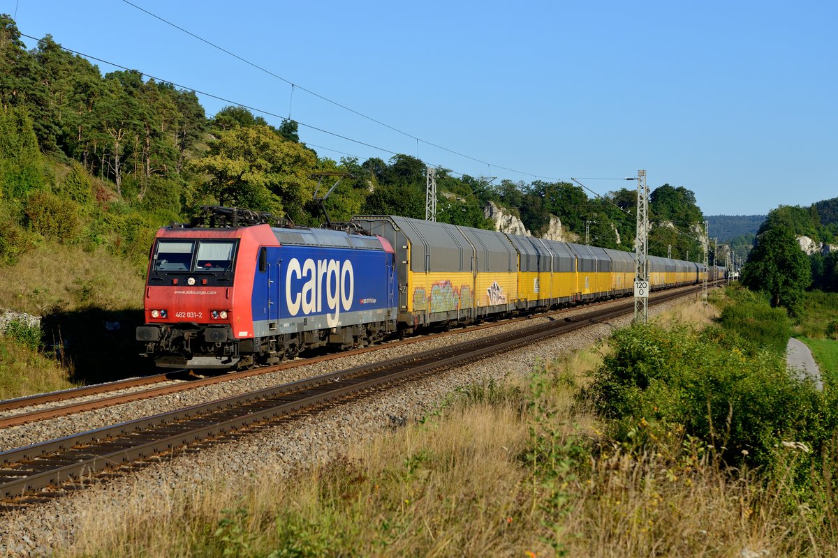 Wenig beliebt bei Eisenbahnfotografen sind die ARS Altmann Autotransportzüge. Zu eintönig, zu oft mit Graffiti beschmiert. Da diese jedoch den Großteil der durchs Altmühltal umgeleiteten Züge ausmachten, sei dieses Foto aus Hagenacker gezeigt: Die für TXL fahrende SBB Cargo 482 031 durcheilt mit ihrem DGS
59886 von Dingolfing nach Bremerhaven Kaiserhafen die für das Altmühltal typischen Felsenformationen (26. August 2016).