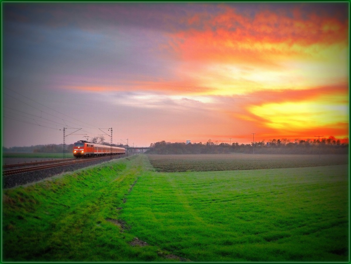 Wenn es Abends früh dunkel wird und die Sonne früh hinter dem Horizont verschwindet dann ist die Zeit der Kälte, des Winters. Doch das heißt noch lange nicht, dass es unmöglich ist, an die Strecke zu fahren und ein wenig zu fotografieren.
Auch die verschiedenen Einstellungen an meiner Bridge-Kamera setzten der Kreativität keine Grenzen.
Ob das Bild nun gelungen ist oder nicht. Darüber lässt sich wohl streiten.
Jedenfalls fährt am 22.11.14 eine unbekannte 111 mit ihrem SE von Heidelberg in Richtung Frankfurt (Main) und wurde bei Sonnenuntergang von mir und meinen weiteren Kollegen bei Heddesheim/Hirschberg fotografiert. 