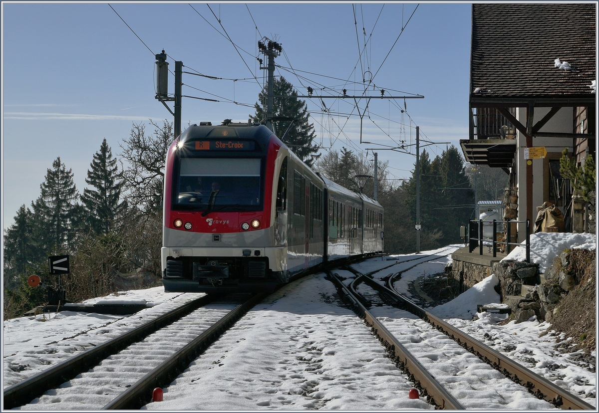 Wer denkt, dieses Bild sei im  Bahnbereich  aufgenommen worden, mag Recht haben und irrt doch: Fordert man bei der Station  Trois Ville  Halt auf Verlangen an, werden nach Halt des Zuges die Türen in Blickrichtung links geöffnet und man befindet sich auf dem nicht vorhandenden Mittelbahnsteig zwischen Gleis 1 und 2. Der Ausgang selbst befindet sich dann beim Empfangsgebäude rechts im Bild. 
Die Fahrgastfrequenzen in  Trois Ville  mögen wohl bescheiden sein, die Aussicht über das (vernebelte) Mittelland und die Schnee bedeckten Alpen ist jedoch allemal eine Halt in Trois Ville wert. 
Das Bild zeigt den ein- und durchfahrenden YSteC TRAVYS Regionalzug 35 von Yverdon nach Ste-Croix.
14. Feb. 2017