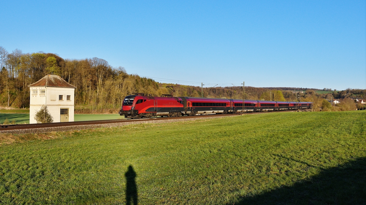 Wie immer war der RJX 63 am 11. April 2020 absolut pünktlich. Da die Schnellfahrstrecke zwischen Stuttgart und Mannheim wegen Sanierungsarbeiten gesperrt ist, beginnt der Zug erst in Stuttgart Hbf und nicht wie üblich in Frankfurt (Main) Hbf. Im flachen Moregnlicht bei Halzhausen auf der Schwäbischen Alb hat der Fotograf nicht nur den schmucken Zug, sondern auch sich selbst verewigt. Einige Jahre zuvor waren leider am Trafohaus einige  Künstler  aus der Bronx zugange. Ihre Hinterlassenschaften haben es dagegen nicht aufs Bild geschafft.