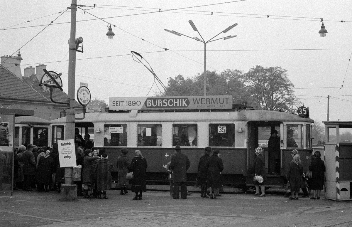 Wien Wiener Verkehrsbetriebe Allerheiligenverkehr 1975: Hochbetrieb an der Endstation vor dem 3. Tor des Zentralfriedhofs am 1. November 1975. Die Leute, die die Grabstätten ihrer verstorbenen Lieben schon besucht haben, müssen jetzt nach Hause befördert werden. Hinter dem Zug der SL 35 (M 4041 + m + m) halten schon die nächsten Straßenbahnen bereit, um die vielen Friedhofsbesucher in Richtung Stadtmitte zu bringen. - Scan von einem S/W-Negativ. Film: Kodak Tri X Pan. Kamera: Kodak Retina Automatic II. 