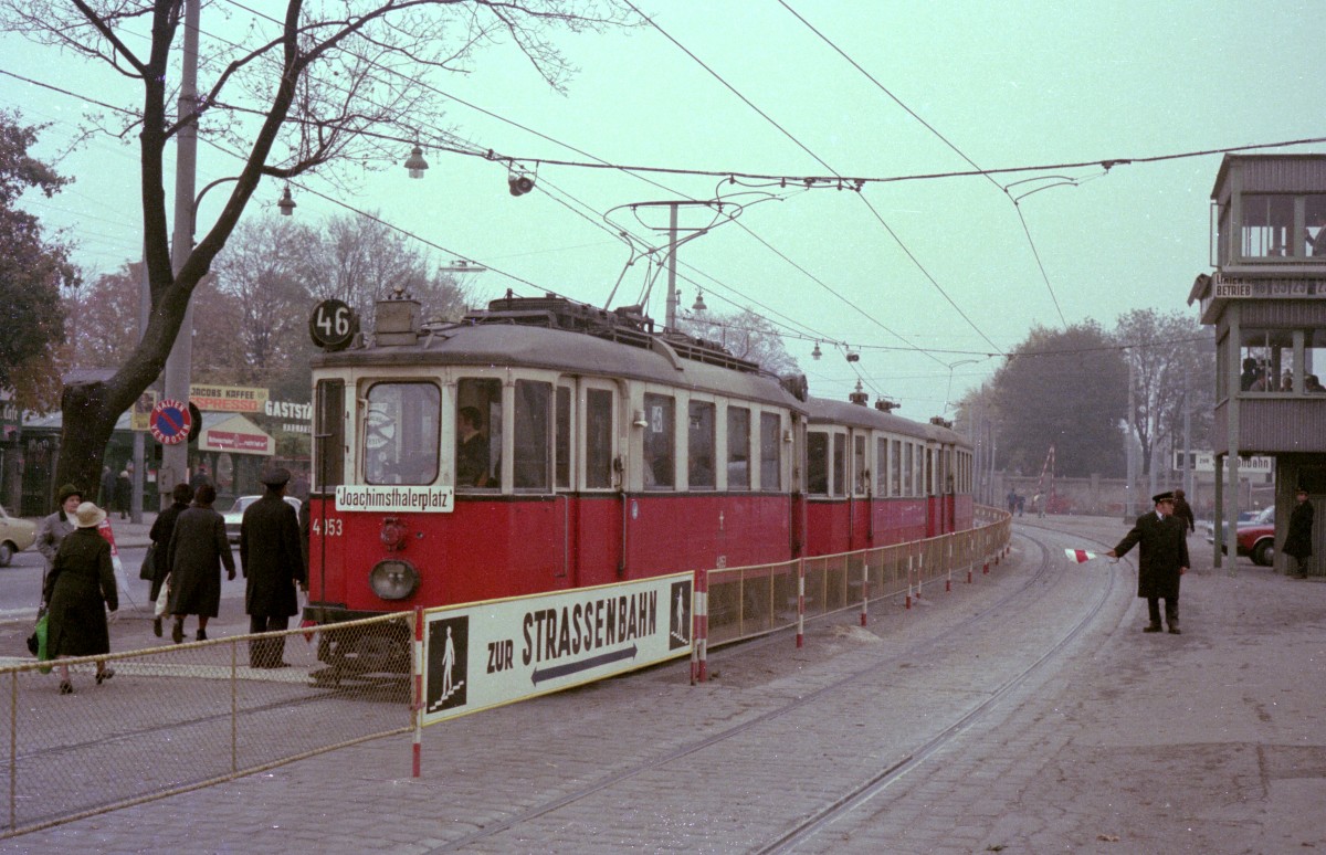 Wien Wiener Verkehrsbetriebe Allerheiligenverkehr 1975: Die nächste Straßenbahn Richtung Zentralfriedhof 3. Tor wird an der Haltestelle am 2. Tor des Zentralfriedhofs, der letzten Haltestelle vor der Endstation, von einem Zugabfertiger erwartet - er steht mit seiner Signalflagge schon bereit. - In die entgegengesetzte Richtung fährt ein Zug der SL 46Z (M 4053 + m + m), der Joachimsthaler Platz als Ziel hat. Datum: 1. November 1975. - Scan von einem Farbnegativ. Film: Kodacolor II. Kamera: Kodak Retina Automatic II.  