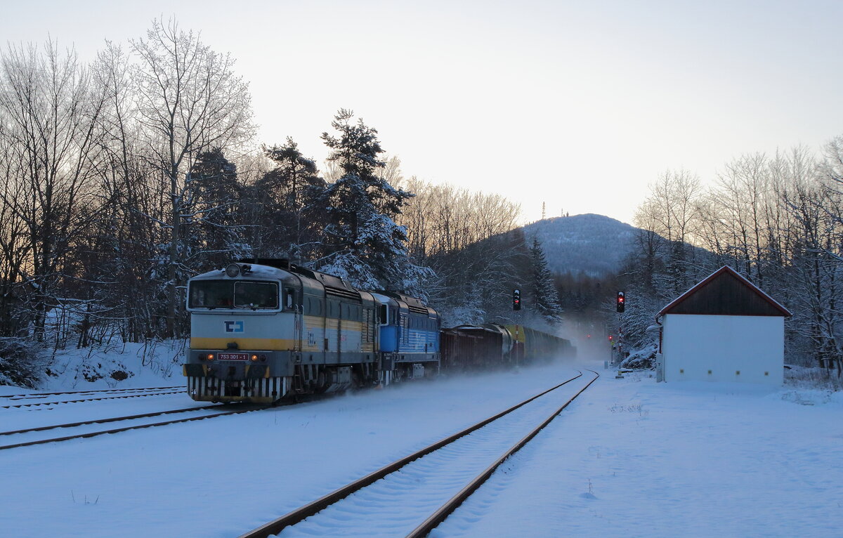 Winterwetter in Chřibská als der Mn 86116 mit der 753 301 und 750 061 durch den Bahnhof eilt. Die Morgensonne war noch hinter dem Berg Jedlova verborgen, aber der Schnee konnte schon etwas Helligkeit erzeugen. Aufgenommen am 27.02.2023