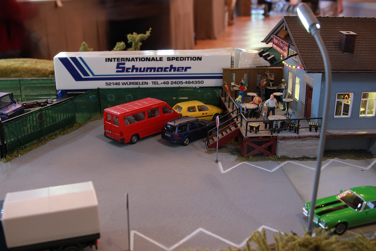 Wir haben ein ganzes Stück weiter gestaltet, sind voll fahrbereit und durften unsere beiden Module ausstellen.
'Rosie's' musste zwischenzeitlich anbauen, jetzt kann man auch auf der Terrasse die 'Happy Hour' geniessen. Im Hintergrund ein Sattelzug auf einen Niederflurwagen für den LKW-Transport (ROLA).
Modellbahntage Markdorf, Oktober 2014