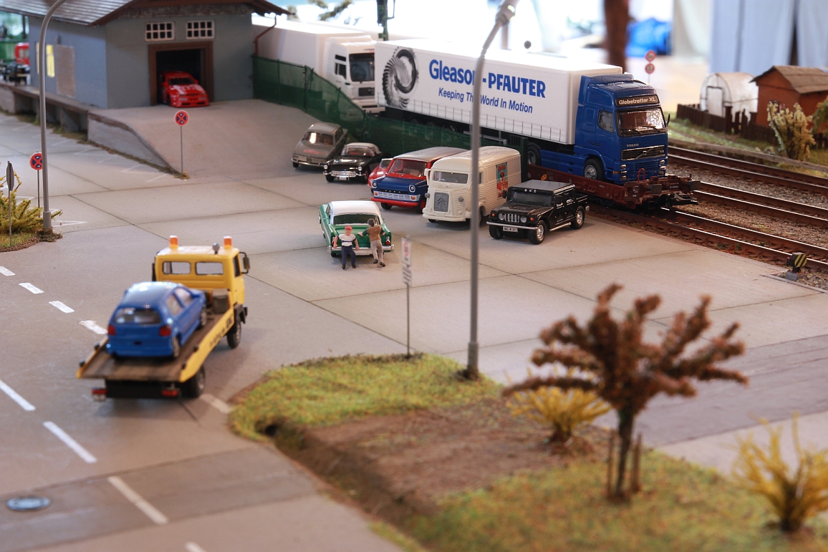 Wir haben ein ganzes Stück weiter gestaltet, sind voll fahrbereit und durften unsere beiden Module ausstellen.
Die ROLA steht zur Abholung bereit. Im Vordergrund die Rückseite von 'Rosie's', die eine Autobastlerwerkstatt beherbergt.
Modellbahntage Markdorf, Oktober 2014