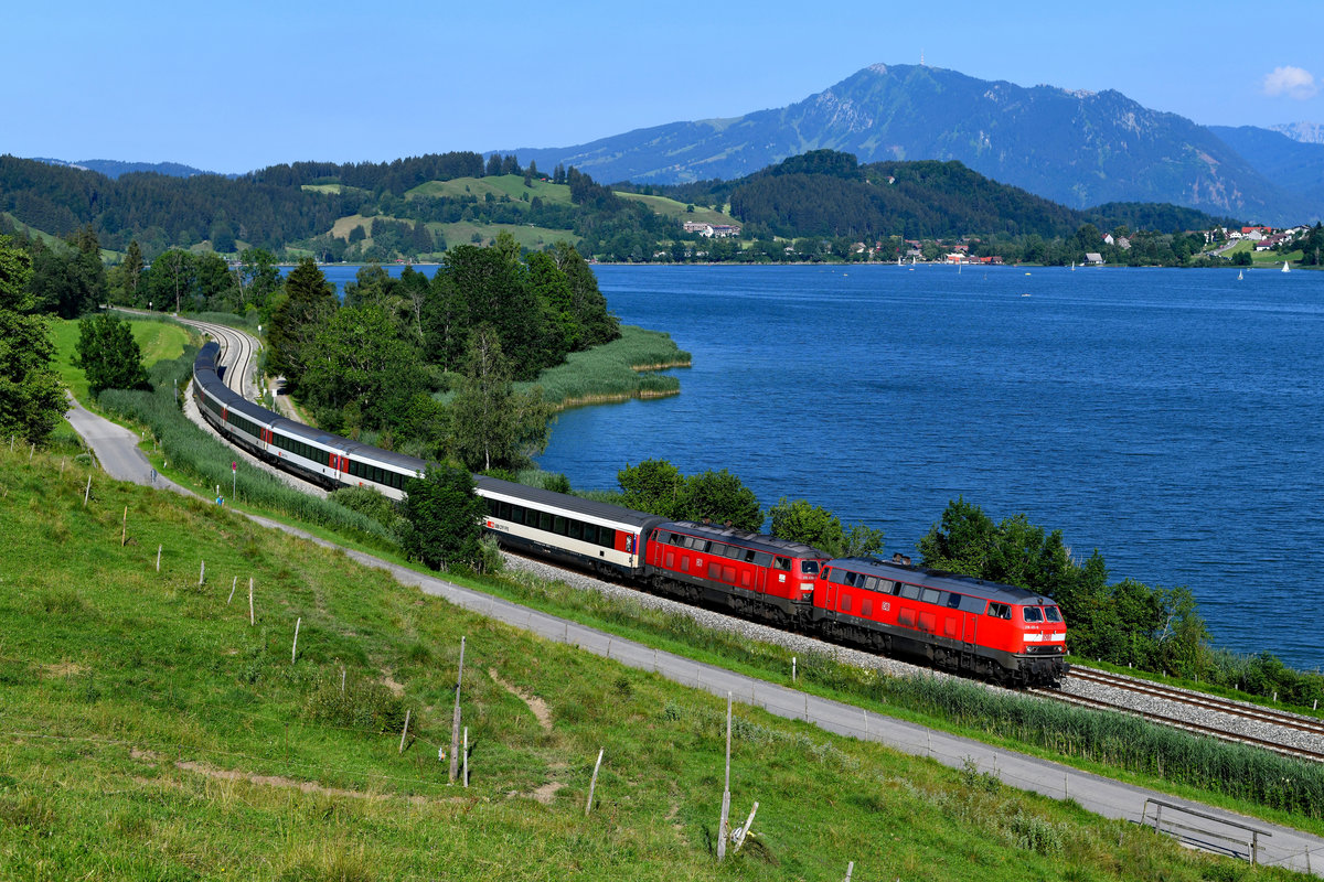 Wird der EC 192 nach Zürich HB über die Allgäubahn umgeleitet, was im Jahre 2018 über mehre Monate hinweg der Fall war, dann bietet es sich im Sommer an, den Zug am Alpsee aufzunehmen. Klassisch ist diese Umsetzung bei Trieblings, mit Blick auf den See und den Grünten. Am 01. Juli 2018 brachten die Mühldorfer 218 401 und die Ulmer 218 436 den Zug pünktlich nach Lindau und kaum ein Wölkchen trübte den Himmel. So konnte man mit em Ergebnis zufrieden sein. 