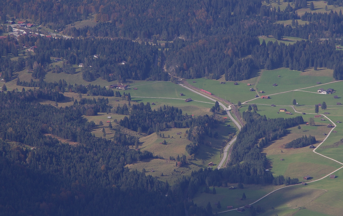 Wo ist das Hamsterbäckchen? II...genau 1300 Meter unterhalb von meinem Standort.
Am 10.10.2014 hat es geklappt, das Wetter war gut und der Wind war war nicht so stark, so machten wir uns auf mit der Karwendelbahn auf den Karwendel bei Mittenwald.
Die Bergstation liegt auf 2244 Meter Höhe. Die RB nach München hat die Schmalenseehöhe (960 Meter)überfahren und von dort aus geht es bergab über Klais in Richtung Garmisch-Partenkirchen. Im linken Eck ist der Bahnhof von Klais zu erkennen, links vom Hamsterbäckchen liegt das Landhaus Wackerl, dort wohnen wir immer wenn wir in Mittenwald Urlaub machen. Bahnstrecke 5504 München - Mittenwald Grenze