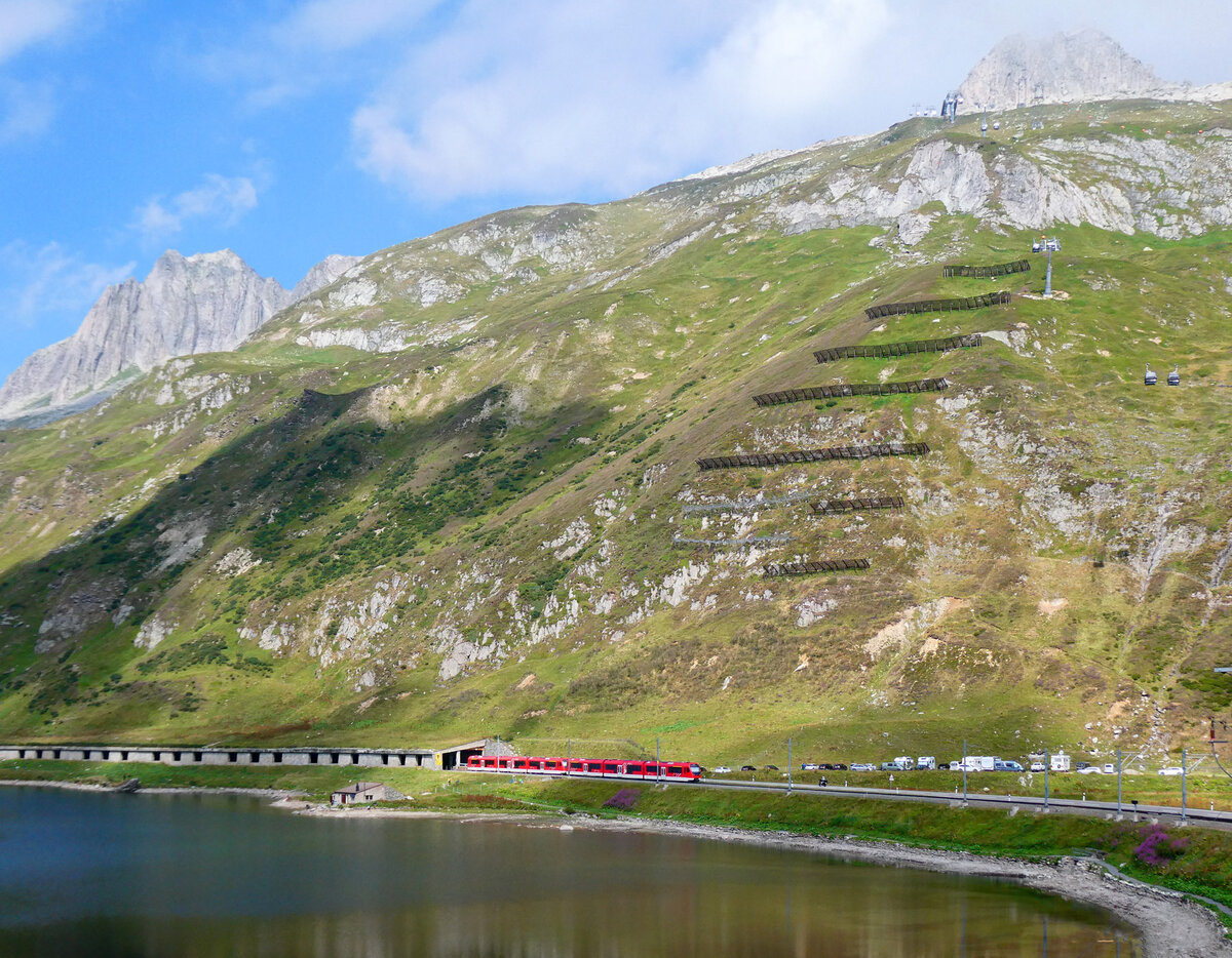 Wunderbarer Blick von der Station Oberalppass (2033 m�M) auf den Oberalpsee und den R45 von Andermatt nach Disentis beim Verlassen der Schutzgalerie. Oberalppass, 7.8.2026
