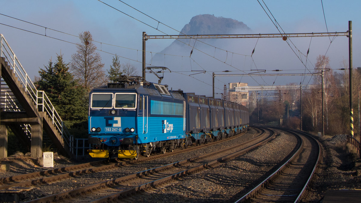 Zelenice nad Bilinou am 16. November 2018: Der Nebel lichtet sich langsam und gibt den Blick auf den Vulkankegel frei. 163 247-0 ist mit ihrem Ganzzug ganz gut unterwegs. 