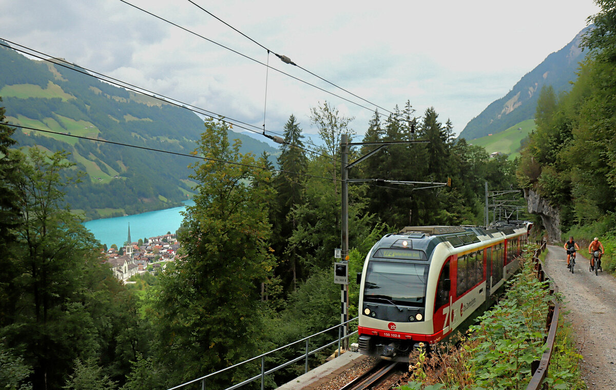 Zentralbahn, Zug 150 102 Luzern - Interlaken im Aufstieg von Lungern auf den Brünig-Pass. Blick auf den Lungernsee und die markante Kirche von Lungern. 6.September 2022 