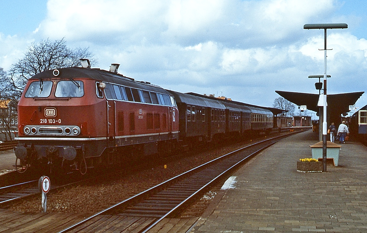 Zu den ersten Serienlokomotiven der Baureihe 218 gehört die 218 103-0, die nach ihrer Ablieferung zum Bw Flensburg kam, wo sie vom 10.05.1971 bis 23.09.1995 stationiert war. Ausgeustert wurde sie am 15.07.2010 in Frankfurt-Griesheim. Am 27.04.1985 steht sie abfahrbereit vor einem Nahverkehrszug im Bahnhof Neumünster.