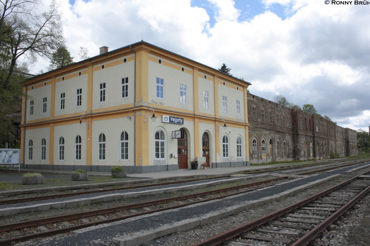 Zu sehen ist die sanierte Seite oder nennen wir es ein Stck von dem gesamten Empfangsgebude des Bahnhofes Vejprty (Weipert).
Hier treffen sich tglich noch die Zge der Erzgebirgsbahn und der Tschechischen Staatsbahn, weiter ist hier leider nichts los.
Aus diesem Grund ist nun der weitere Abbruch des Empfangsgebudes vorgesehen.
Wie hier auf dem Bild zu sehen, stehen nur noch die Grundmauern des alten Gebudes, ein kleiner Teil wurde restauriert, der Rest was den markanten Giebel betrifft wurde schon abgetragen!

Aufgenommen am 20.05.2013.