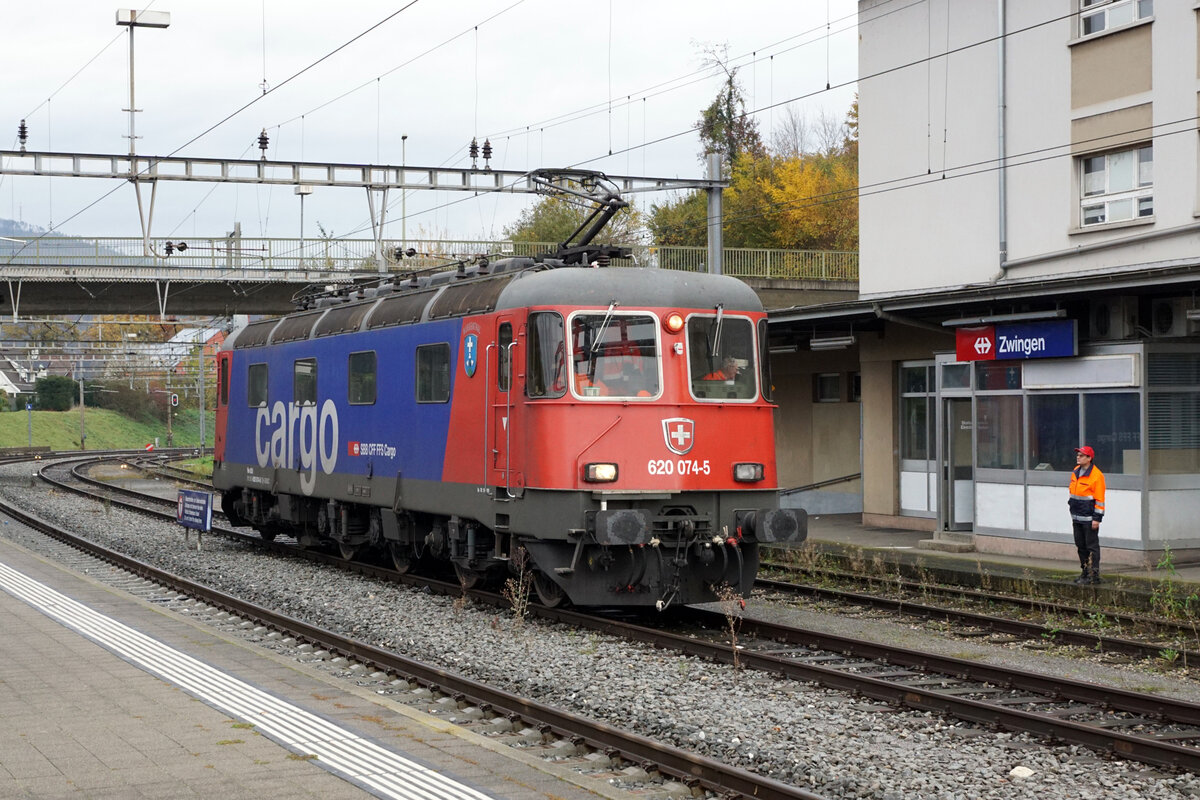 ZUCKERRÜBENKAMPAGNE 2021
Zuckerfabrik Aarberg
Die Zuckerrüben der Umgebung von Zwingen im Kanton Baselland werden nur an einem einzigen Tag verladen. Die stark veralteten Bahnanlagen sind auch im Jahre 2021 noch bestens geeignet für einen sehr effizienten Verlad. Da der gesamte Zug verteilt auf drei Abstellgeleisen bereitgestellt werden kann, gelangt auch keine Rangierlok zum Einsatz. Die Bereitstellung sowie die Rangierfahrten für die Zusammenstellung des Zuges werden mit der Streckenlokomotive vorgenommen. Da diese nicht alltäglichen Rangierfahrten vom zentralen Stellwerk Olten nicht abgedeckt werden, mussten sie von einem extra angereisten  Fahrdienstleiter an Ort angeordnet werden. Die einmaligen Impressionen mit der Re 620 074-5  MURGENTHAL   wurden am 30. Oktober 2021 in Zwingen verewigt.
Lokzug von Münchenstein bei der Ankunft in Zwingen.
Foto: Walter Ruetsch

