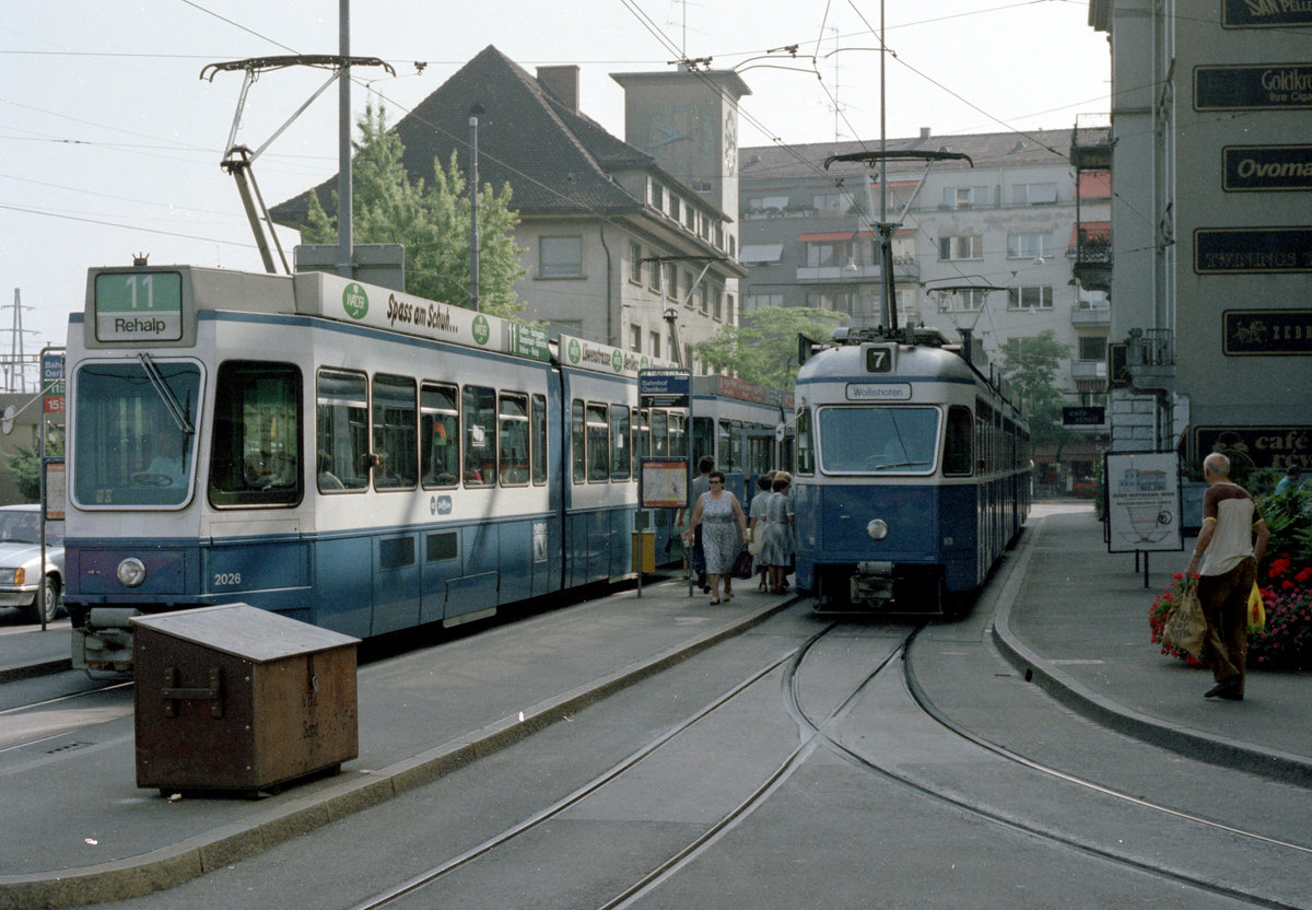 Zürich VBZ im Juli 1983: An der Tramhaltestelle Bahnhof Oerlikon sieht man, was u.a. für die Aufrechterhaltung des Trambetriebes notwendig ist, nämlich vor allem Tramgarnituren mit den Wagenführern, aber auch den Salzbehälter für den Verkehr im Winter; außerdem gibt es etwas, was für die Fahrgäste sehr wichtig / praktisch ist, nämlich Haltestelleninseln mit Linientafeln und -übersichten. - Scan von einem Farbnegativ. Film: Kodak safety Film 5035. Kamera: Minolta XG-1. 