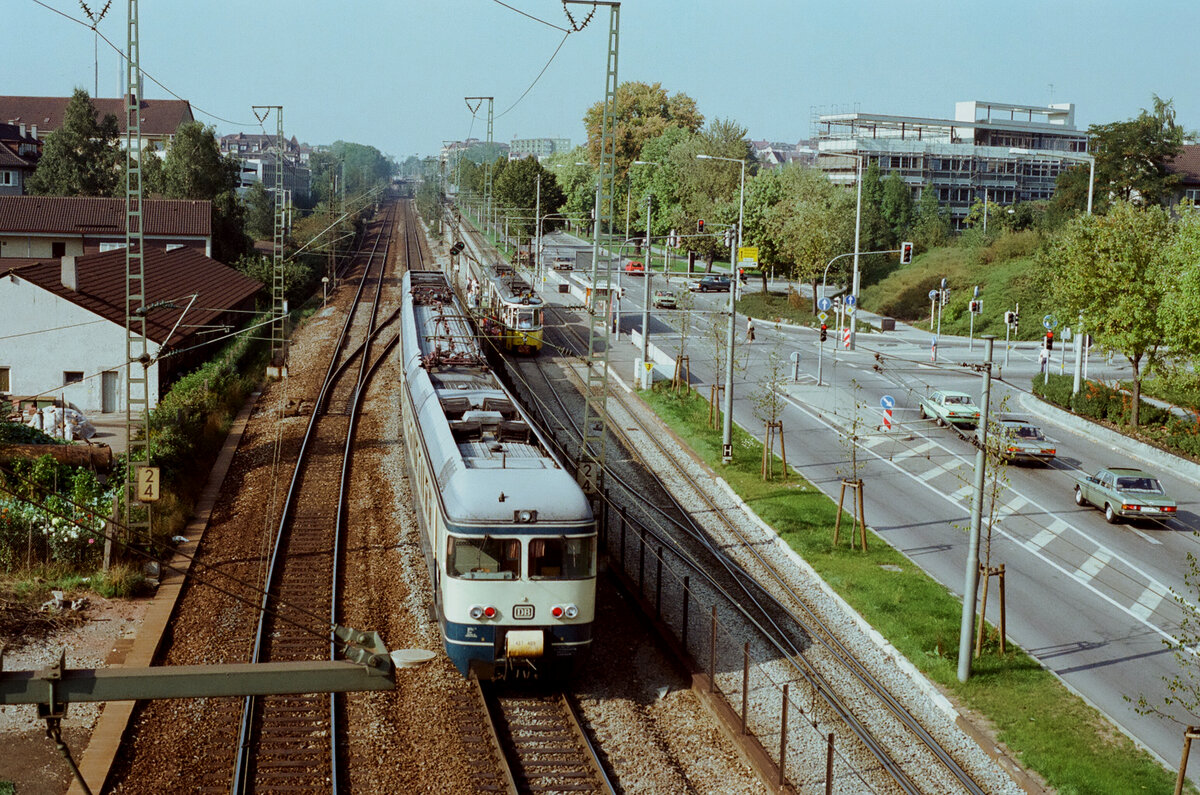 Zug der DB-Baureihe 427 alt auf DB-Gleisen neben der Stuttgarter Stra�enbahnlinie 13 bei der Stra�enbahnstation Kienbachstra�e (1984) 