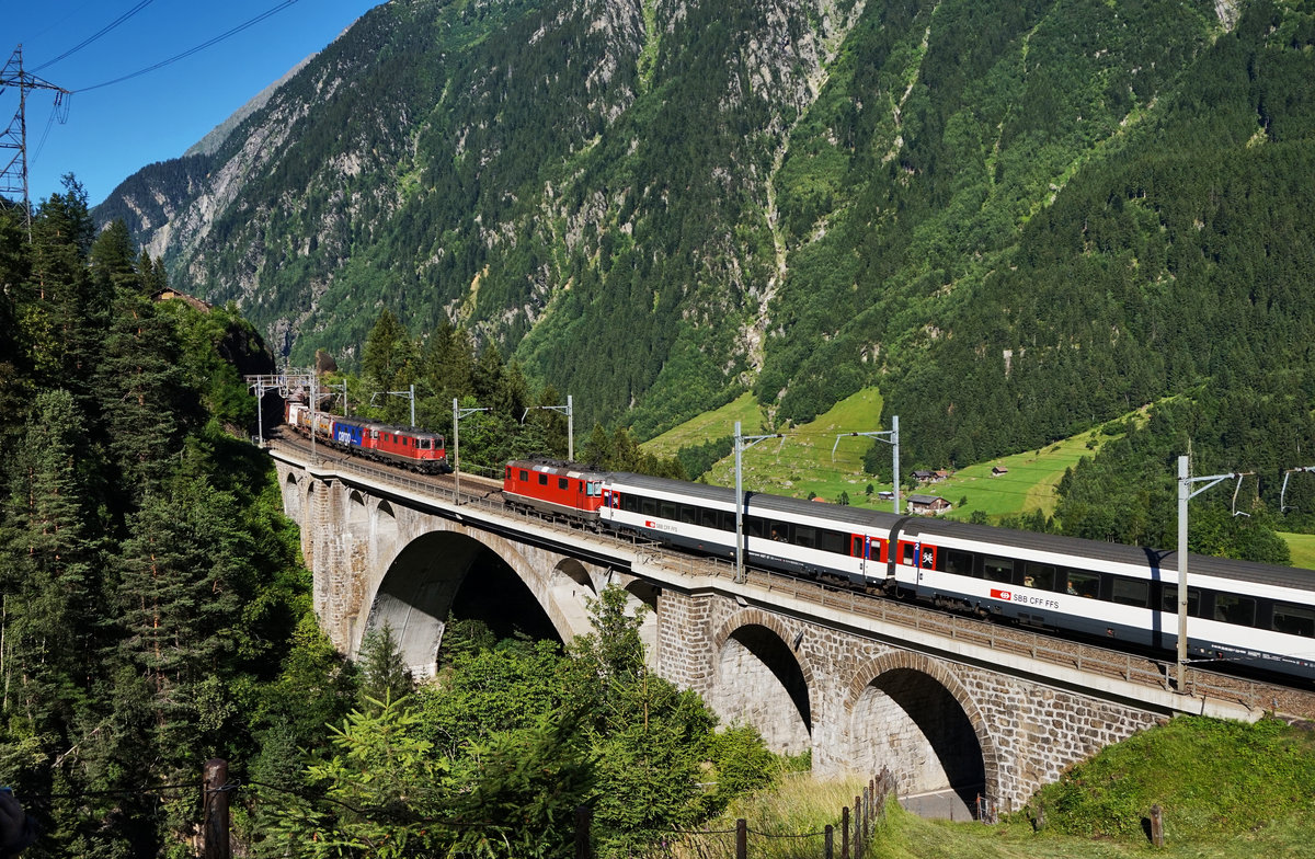 Zugkreuzung auf der mittleren Meienreussbrücke.
Aus Richtung Erstfeld kommend fährt eine Re 4/4 II mit dem IR 2429 (Zürich HB - Locarno) in Richtung Göschenen hinauf, während auf dem anderen Gleis eine Re 10/10, bestehend aus Re 4/4 II 11341 und Re 620 061-2  Gampel-Steg , mit ihrem Güterzug talwärts unterwegs ist.
Aufgenommen am 19.7.2016.