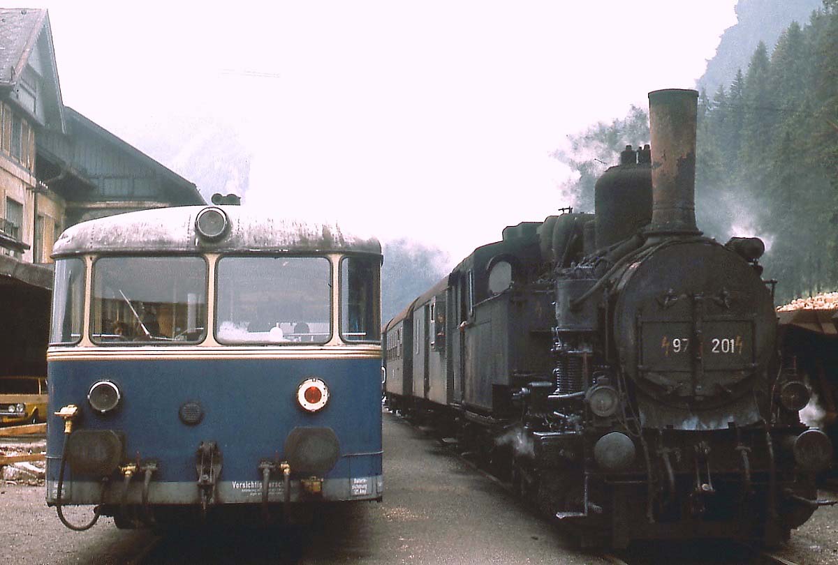 Zugkreuzung im Bahnhof Präbichl im August 1975: Während ein 5081 als Regionalzug 4104 von Eisenerz nach Vordernberg unterwegs ist, befördert 97.201 den Regionalzug 4105 in der Gegenrichtung. Ein Jahr zuvor waren die ersten für den Steilstreckenbetrieb umgebauten 5081 in den Umlauf der Reihe 97 eingedrungen, im Sommer 1975 beförderten die Dampflokomotiven nur noch das Personenzugpaar 4105/4106. Und auch damit war es mit dem Wechsel zum Winterfahrplan 1975/76 vorbei. Auf dem Zahnstangenabschnitt von Vordernberg bis Präbichl schoben die Dampflokomotiven den Zug hinauf zum Scheitelpunkt, der begehrteste Platz für Eisenbahnfreunde war auf diesem Abschnitt natürlich die Plattform des letzten Personenwagens unmittelbar vor der schwer arbeitenden Lok, ein Erlebnis, das sich tief ins Gedächtnis grub und nur schwer in Worte fassen lässt...