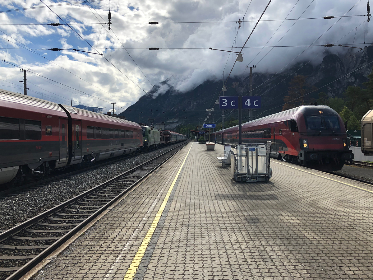 Zugverkehr in Ötztal-Bahnhof während der Arlbergsperre. Am Abend des 30.06.2021 standen auf Gleis 2 der RJX 862 aus Flughafen Wien und dahinter gleich der IC 119  Bodensee  nach Innsbruck Hbf mit der Umweltschutz 1016. Auf Gleis 4 wartet RJX 169 auf die Ausfahrt nach Wien Hbf. Ötztal-Bahnhof am 30.06.2021