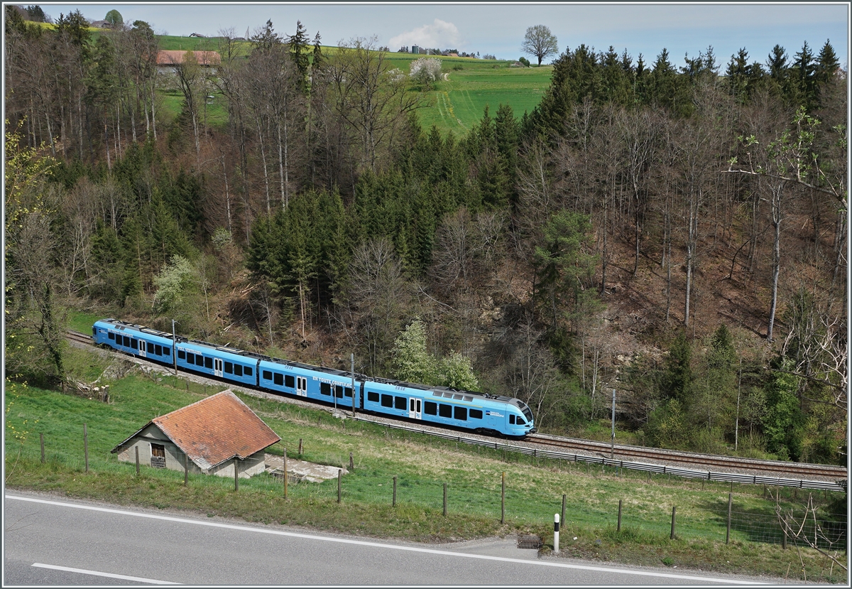 Zum Abschluss noch einen weiteren Einblick in den bereits gezeigten Einschnitt von einer etwas höher gelegen Position aus, welcher auch einen Blick auf die dahinter liegende Landschaft gewährt. Im Bild der im sehr gefälligen Werbeanstrich der  Groupe Grisoni  gehaltene TPF RABe 527 198 welcher sich als RER 21 14649 auf der Fahrt von Ins nach Fribourg befindet. 

19. April 2022