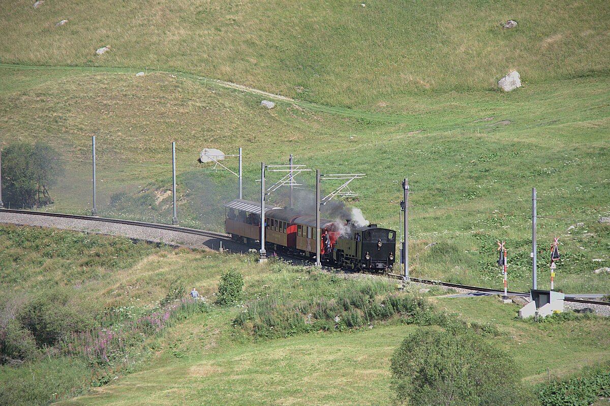 Zum Jubil�um 100 Jahre FO fuhr morgens ein Extrazug von Realp nach Andermatt um die G�ste abzuholen. Hier bei einem Bahn�bergang zwischen Realp und Hospental am 04.07.2026 im alpinen Wiesland.