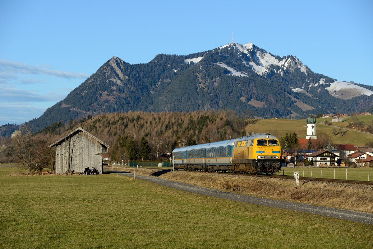 Zum Tagesabschluss gelang dann noch das Klassikermotiv mit dem Blick auf Altstädten und den Grünten mit der DB Bahnbau 218 391 und ihrem ALX 84168 nach Oberstdorf (06. Januar 2014).