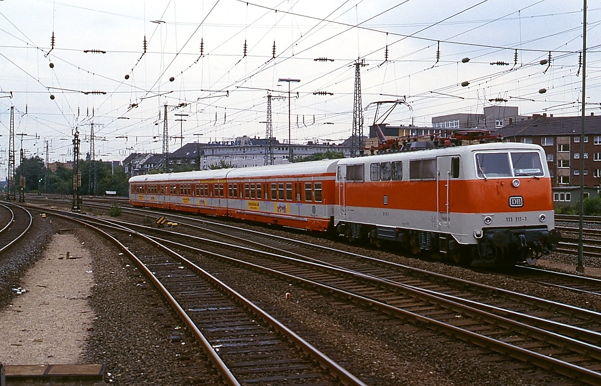 Zum Vergleich mit den aktuellen Aufnahmen ein Bild der damals erst einige Monate alten 111 111-1 mit einem in Essen Hbf. einfahrenden S-Bahn-Zug um 1979