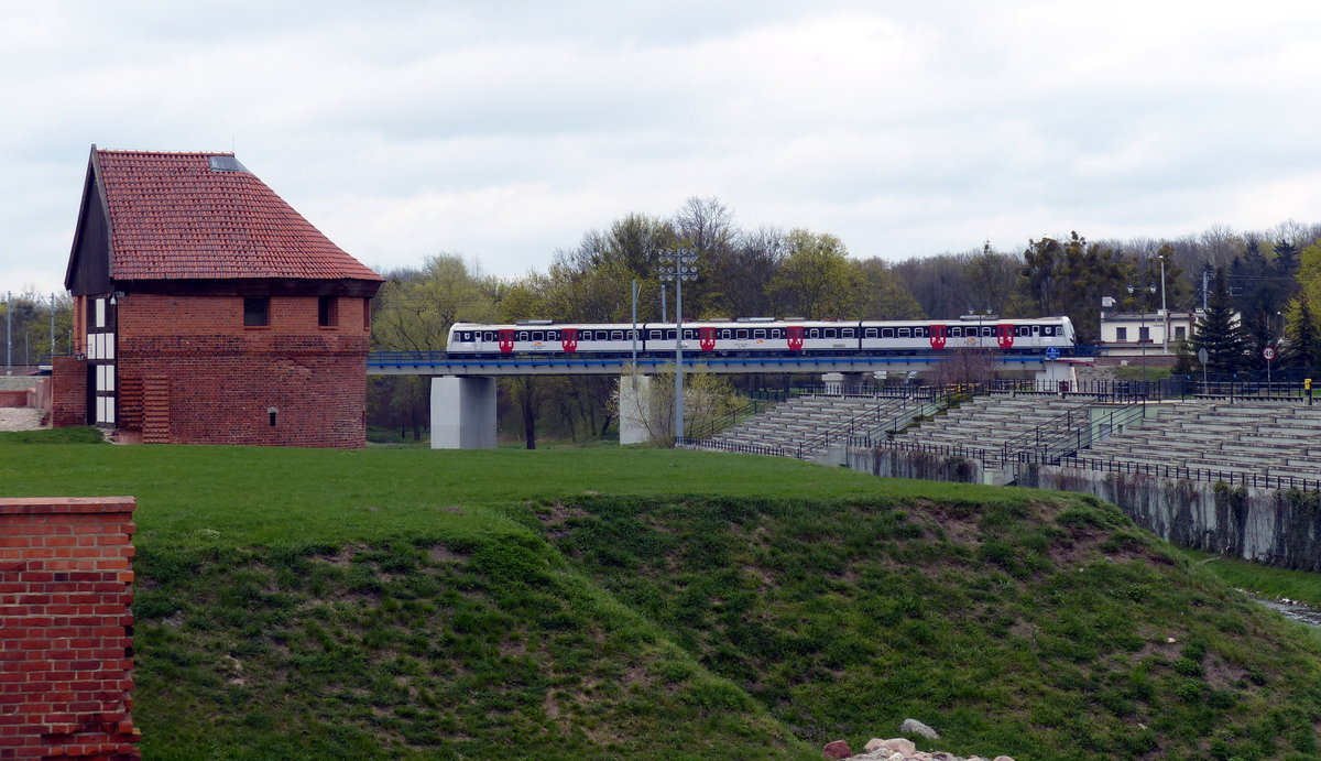 Zur Marienburg (polnisch Malbork) kann man mit allen möglichen Zugklassen anreisen. An der beeindruckenden riesigen Burganlage - ein touristisches Highlight der Region - fährt man direkt vorbei. Hier verlässt ein Regionalzug der Reihe EN 57 den Bahnhof auf seiner Fahrt in Richtung Gdynia. 12.4.2017, Malbork