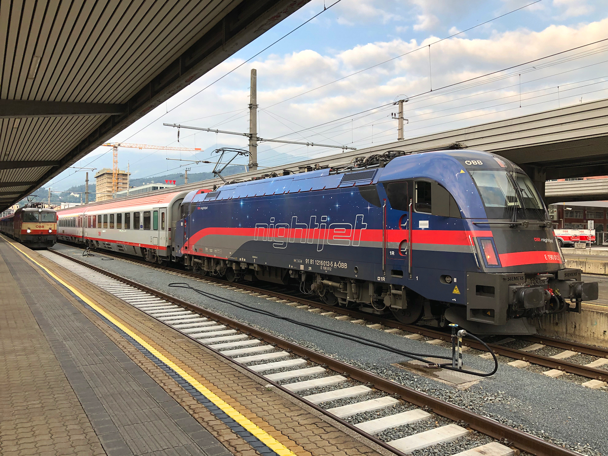 Zwei Besonderheiten am frühen Morgen in Innsbruck Hbf. 1216 012-5  NightJet  wartet mit EC 288 auf die Abfahrt nach München Hbf. Kurz zuvor kam 1144 092-4  Schachbrett  mit REX 5361 aus Landeck-Zams am Zugendbahnhof an. Aufgenommen am 21.07.2021