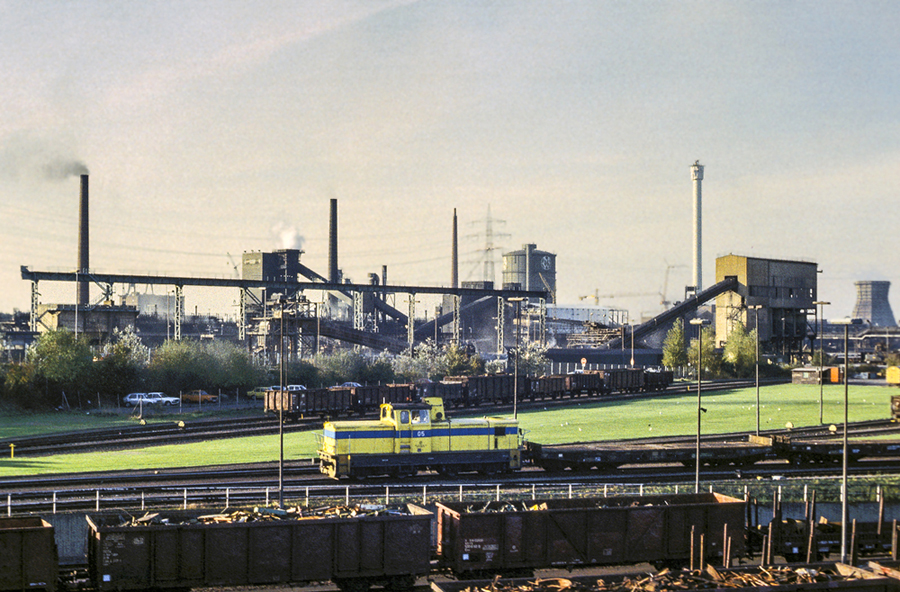 Zwei Bilder, ein Ort, eine Situation, dreißig Jahre Unterschied. Im Juni 1983 rangiert Lok 05 der Eisenbahn und Häfen (EH) ein paar Flachwagen auf dem Gelände der damaligen Mannesmann Hüttenwerke. Die Hausfarben der EH waren in den 80ern gelb und blau. Bild ID 762482
http://www.bahnbilder.de/bild/Deutschland~Unternehmen~Eisenbahn+und+Hafen+Duisburg/762482/zwei-bilder-ein-ort-eine-situation.html
zeigt annähernd die gleiche Szene im Dezember 2013.