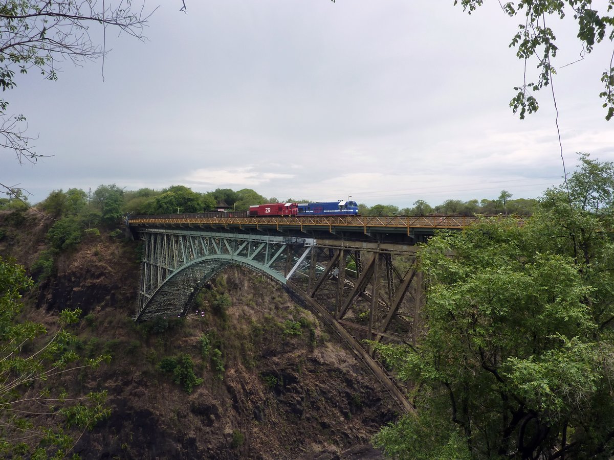 Zwei Dieselloks der Zambia Railways überqueren am 12.12.2014 mit einem Güterzug die Victoria Falls Bridge in Richtung Simbabwe. Da die Brücke sozusagen neutrales Gebiet darstellt fanden 1975 während des Unabhängigkeitskrieges .Friedensgespräche in einem Personenwagen auf der Brücke statt