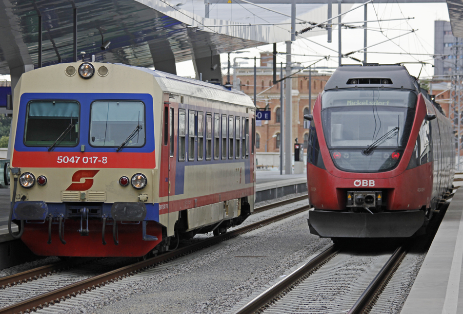 Zwei Generationen von BB-Triebzgen am Wiener Hauptbahnhof. 5047-017 auf der Durchfahrt auf Bahnsteig 10, 4124-002 verlsst Bahnsteig 9 als REX nach Nickelsdorf. Dahinter die historische Kulisse des Wiener Arsenals. 20.8.2013