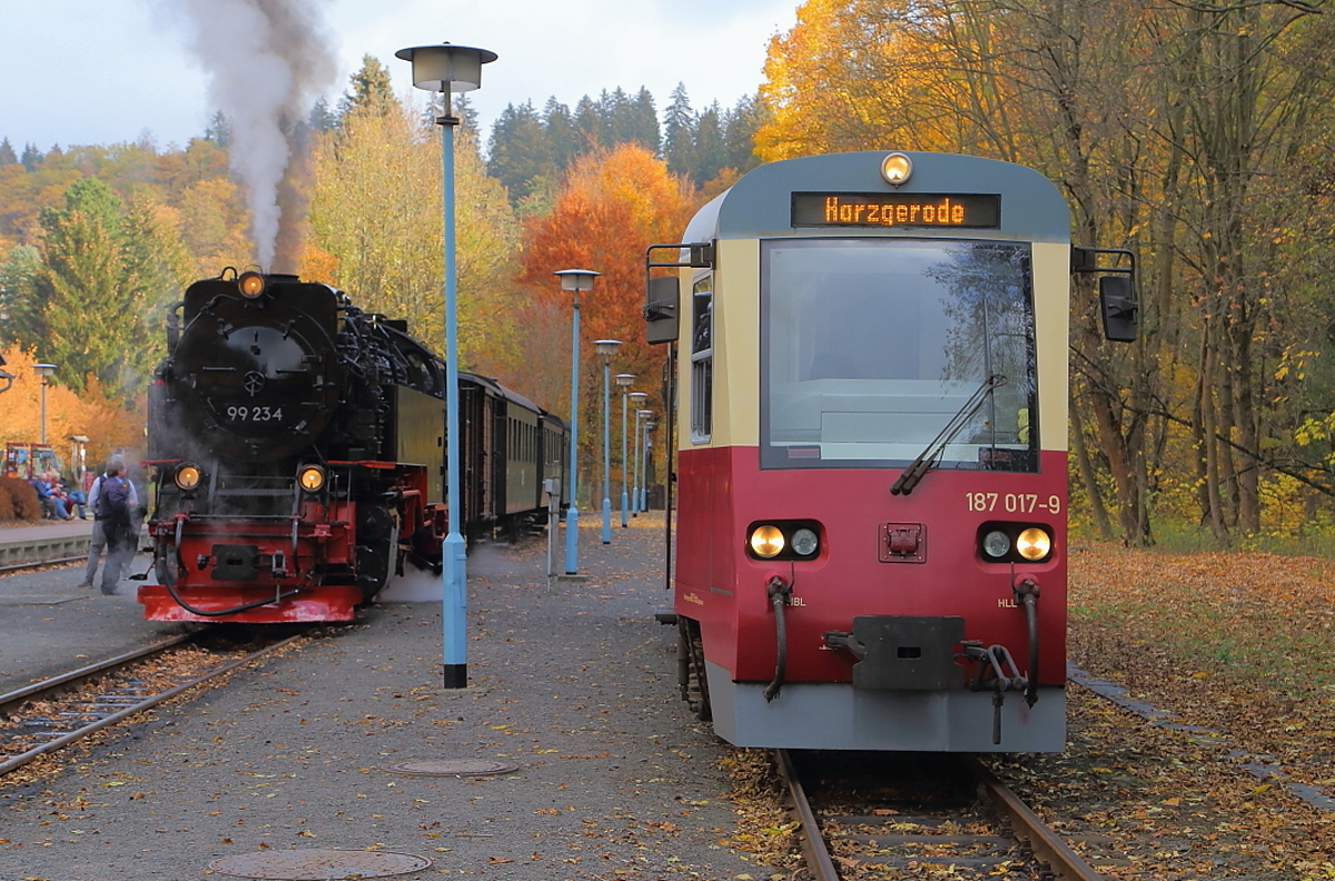 Zwei Generationen von Schmalspur-Bahnfahrzeugen nebeneinander. Links 99 234 (Baujahr 1954, LKM Babelsberg) mit IG HSB-Sonder-PmG und rechts Triebwagen 187 017 (Baujahr 1999 DB AG Werk Halberstadt), als Planzug Richtung Harzgerode. (Aufnahme vom 21.10.2018 im Bahnhof Alexisbad)