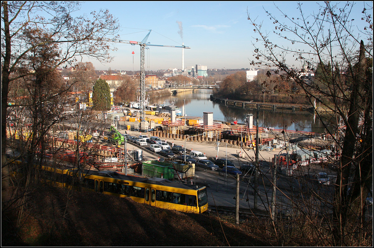 Zwei Großbaustellen treffen hier zusammen -

Zum einen entsteht hier die Ausfahrt des B10 Straßentunnels und zum anderen wird hier schon an der neuen Neckarbrücke für Stuttgart 21 gebaut. Man sieht in Bildmitte schon die Pfeiler emporwachsen. Links oberhalb der Stadtbahn die Baugrube des Straßentunnels. Die Stadtbahnlinie U14 passiert die Baustellen eingleisig, wobei das Gleis demnächst auf eine Brücke über die Baugrube verlegt wird.

Ich stehe hier übrigen auf dem Portal des ersten Eisenbahntunnels unter dem Rosensteintunnel. Für den zweiten Stuttgarter Hauptbahnhof wurden auch schon hier ein neuer Tunnel und eine neue Bahnbrücke gebaut, für den dritten Hauptbahnhof wiederholt sich die Geschichte.

10.12.2016 (M)