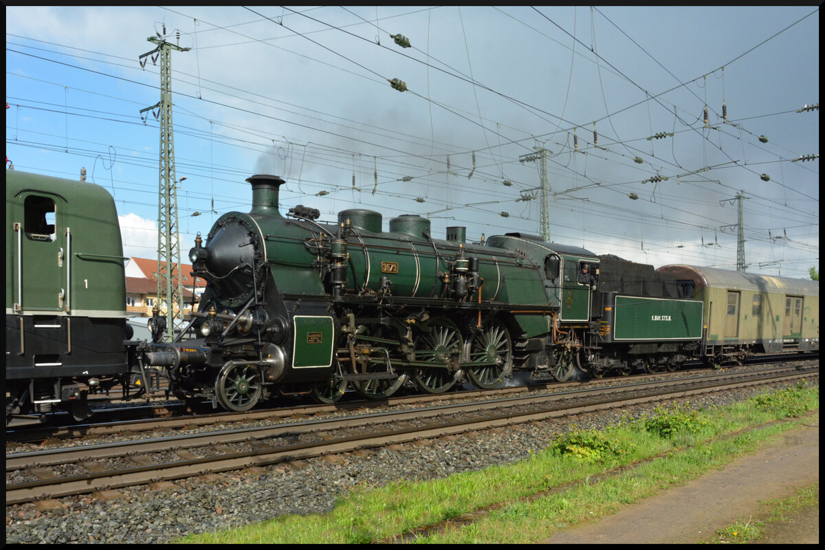 Zwei grüne Loks im Grünen – oder: Dualmode a la BayernBahn. Anlässlich der Museumstage am 20. & 21. April 2024 im DGEG Eisenbahnmuseum Bochum in Bochum-Dahlhausen überführte das Bayerische Eisenbahnmuseum Nördlingen (BEM) seine legendäre Schnellzugdampflok, die bayerische S3/6 3673, als Gastlokomotive von Bayern nach Nordrhein-Westfalen. Eingereiht in den ebenso bekannten Henkelzug fuhr die Dampflok am 18.04.2024 gemeinsam mit der BayernBahn 151 001 und einem ehemaligen Postwagen als Begleiter von Nördlingen über Donauwörth, Würzburg und Darmstadt-Kranichstein nach Bochum-Dahlhausen.
Die beiden grünen Lokomotiven konnten bei der Überführungsfahrt, sozusagen als Dualmode-Gespann a la BayernBahn, in Würzburg im Grünen beobachtet werden.
