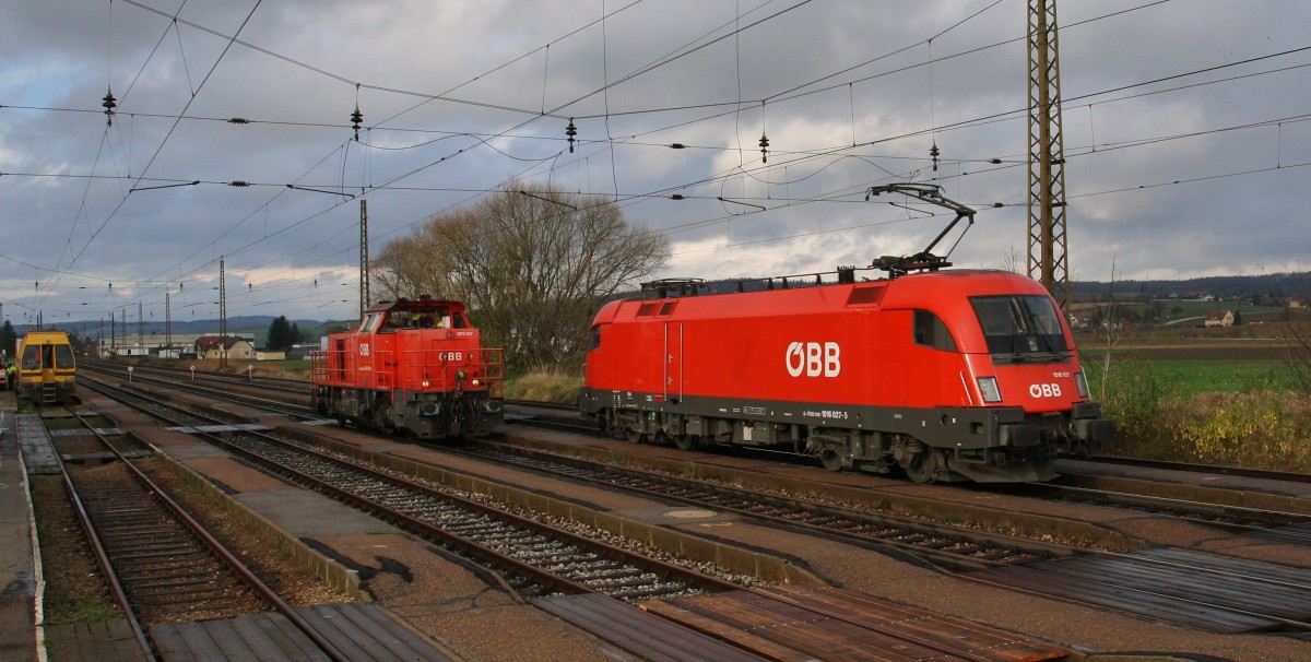Zwei Lokzüge rollen am 18.11.2014 durch Kirchstetten. Die 1016 027-5 Richtung St. Pölten auf Gleis 2, die 2070 037-4 als Verschub auf Gleis 1 bis Neulengbach. Retour kam die 2070 037-4 mit einem Holztransportwagen im Verschub nach St. Pölten.
